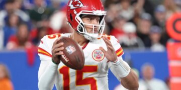 Patrick Mahomes #15 of the Kansas City Chiefs in a white jersey and red helmet with a football in hand.