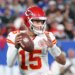 Patrick Mahomes #15 of the Kansas City Chiefs in a white jersey and red helmet with a football in hand.
