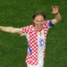 Luka Modric in a checkered red and white jersey on a green field.