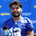 Los Angeles Rams player Stetson Bennett in a blue jersey speaking at a press conference.