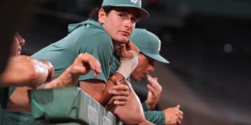 Boston Red Sox's Roman Anthony, sidelined with an injured right wrist, watches from the dugout rail.