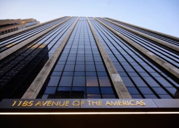The facade of 1185 Avenue of the Americas, a skyscraper in Manhattan, New York, with its name illuminated in gold at the bottom.