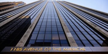 The facade of 1185 Avenue of the Americas, a skyscraper in Manhattan, New York, with its name illuminated in gold at the bottom.