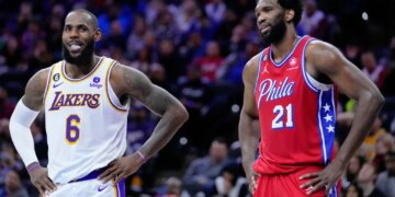 LeBron James of the Los Angeles Lakers and Joel Embiid of the Philadelphia 76ers stand on the court during an NBA basketball game.