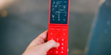 A red flip phone, open, showing directions.