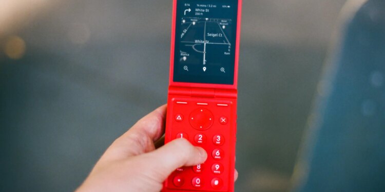 A red flip phone, open, showing directions.