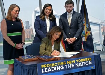 Governor Kathy Hochul signing an executive order to pause AI data center construction, with Julie Tighe, State Senator Kristen Gonzalez, and Coner Eckert in the background.