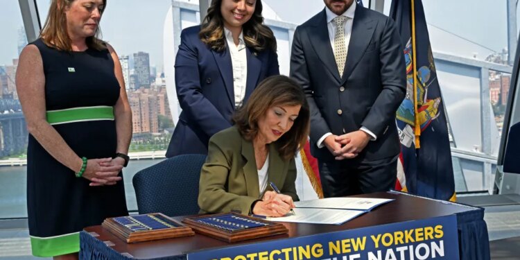 Governor Kathy Hochul signing an executive order to pause AI data center construction, with Julie Tighe, State Senator Kristen Gonzalez, and Coner Eckert in the background.