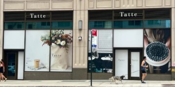 The exterior of Tatte Bakery & Cafe on the Upper East Side, featuring window displays of floral arrangements, a coffee, and a blueberry tart.